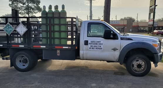 Harris County Professional Gases delivery truck loaded with green gas cylinders